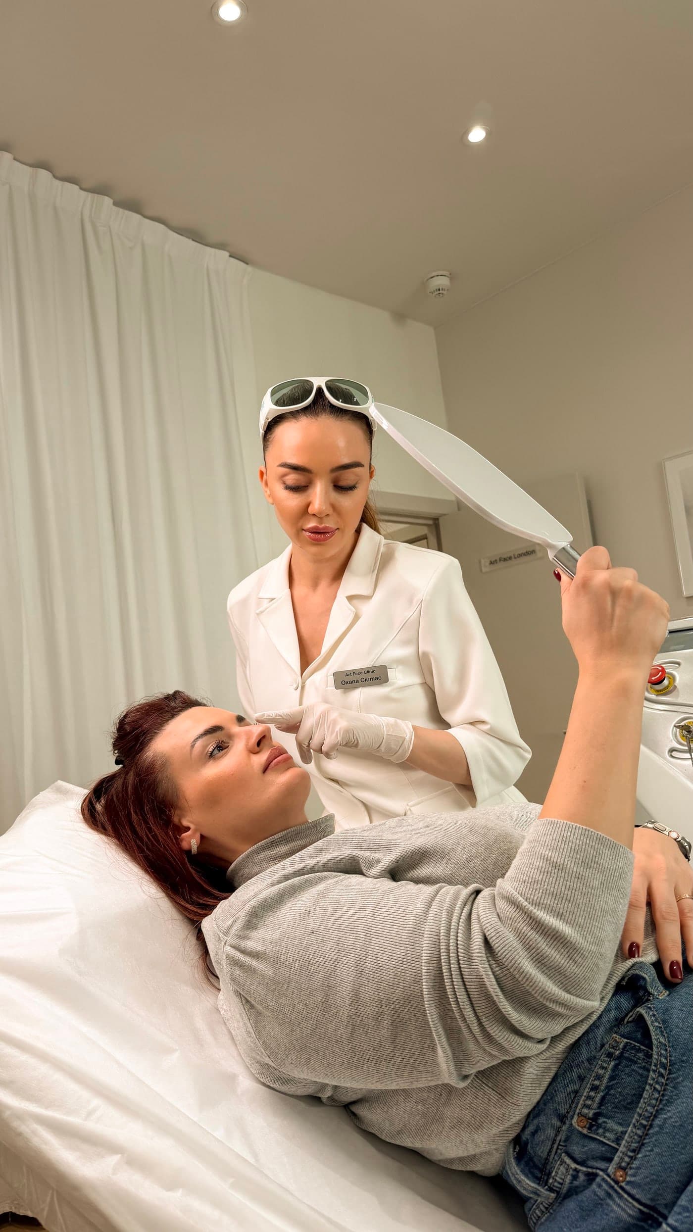 Practitioner checking the brows as the client reviews them in a hand mirror after treatment at ART FACE Clinic