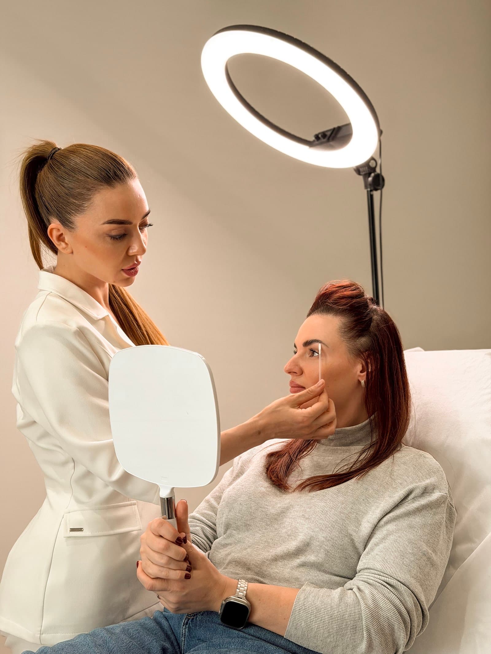Practitioner assessing a client's eyebrows under a ring light before laser pigment removal at ART FACE Clinic, Pimlico, London